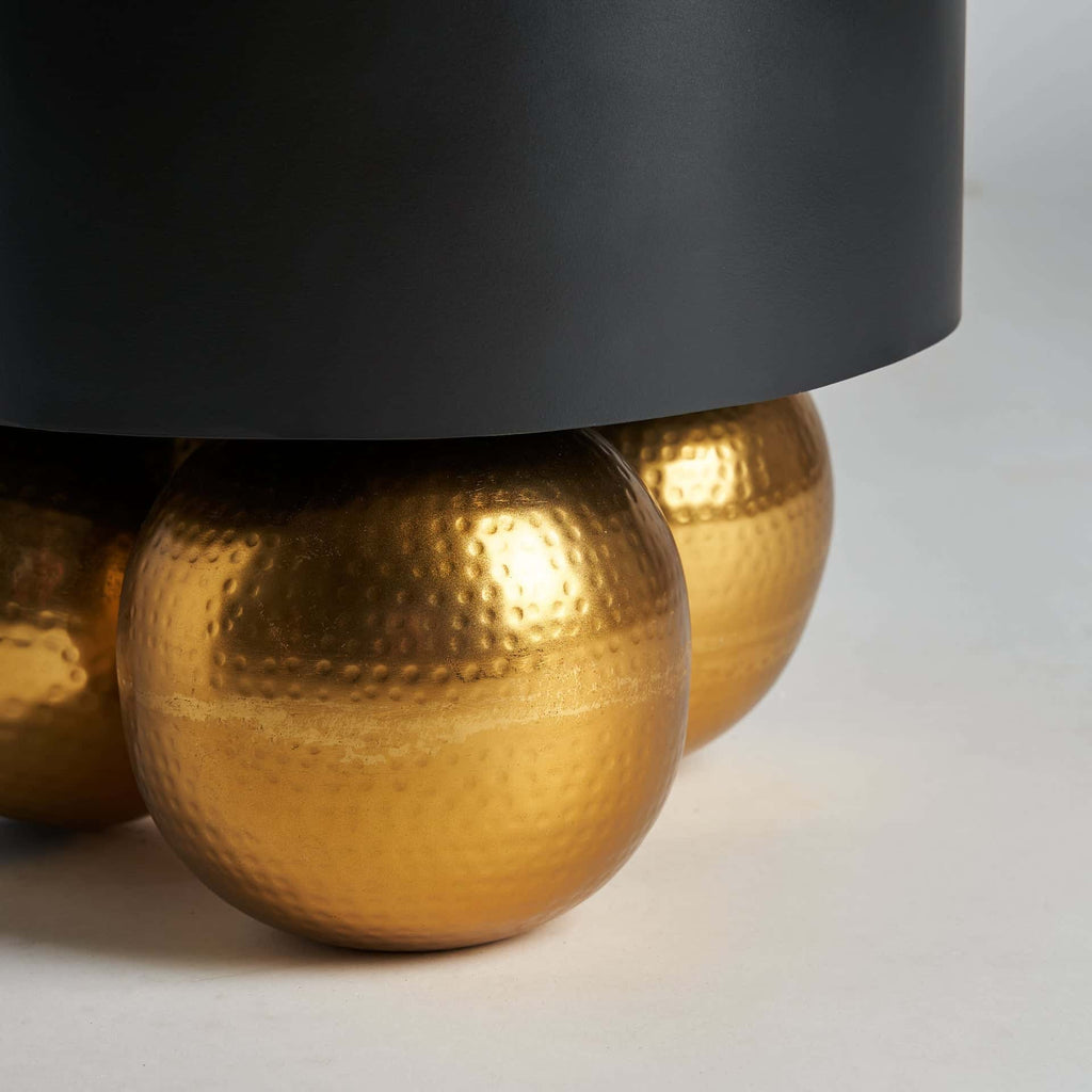 Runder Beistelltisch in Schwarz kombiniert mit drei goldenen Kugelbeinen - Maison Oudh